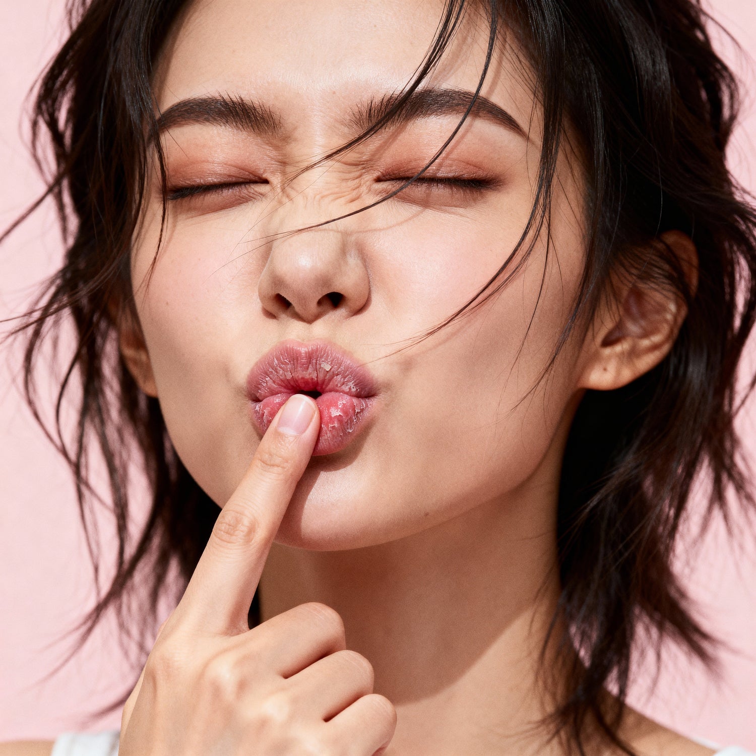 Close-up of a woman touching dry, chapped lips, highlighting lip texture and dehydration.